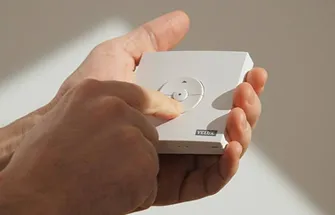 Hand houdt wit Velux bedieningspaneel met draaiknop en logo