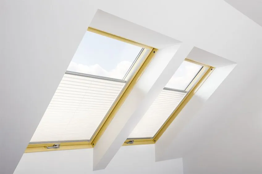 Twee Velux dakramen met geïnstalleerde witte plissegordijnen in open stand