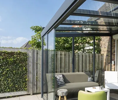 Moderne terrasoverkapping met zitbank en groene privacyheg in een tuin