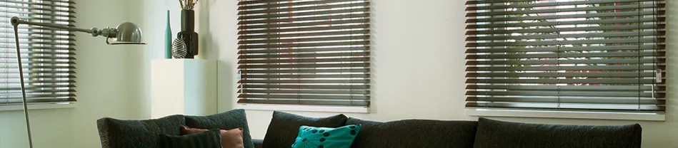 Moderne aluminium jaloezieën gesloten voor een raam in een woonkamer met donkere bank