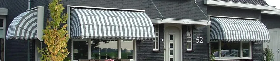 Wit-grijze gestreepte markiezen voorzien van een halfronde vorm boven de ingang van een huis